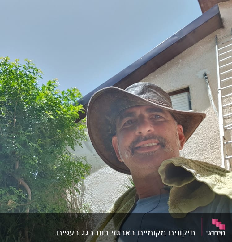 סולם מתכת נשען על קיר ליד גג הבית